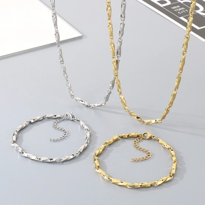Gold and silver stainless steel Chopin chain necklace and bracelet jewelry set on a desk