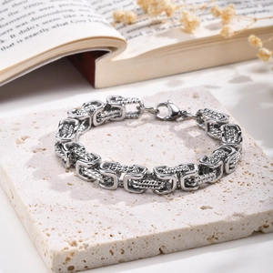 Detailed view of silver Byzantine chain bracelet with textured links on white stone