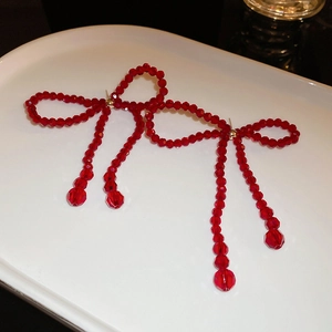 Détail de boucles d'oreilles nœuds en perles de cristal rouge à longs glands
