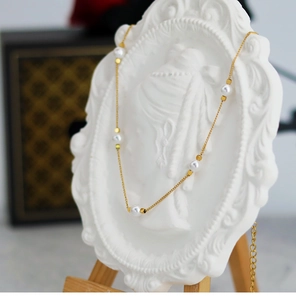 Detail of elegant gold chain necklace with white pearls and square beads on a bust stand