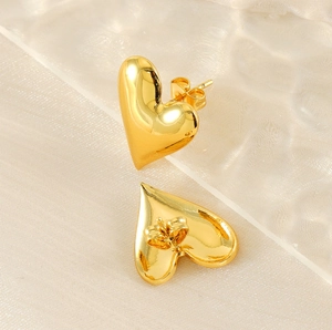 Detailed close-up of 18K gold-plated heart studs with butterfly backs on silk fabric