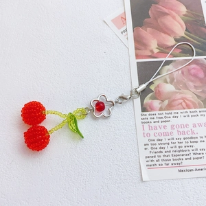 Detail of handmade beaded cherry charm with red beads, green leaves and metal lobster clasp