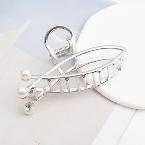 Silver cross hair claw clip with three pearls on a minimalist white display base