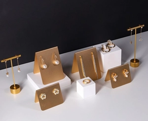 Collection of gold-plated alloy jewelry with pearls and rhinestones on a minimalist background