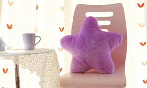Close-up of a soft purple star-shaped plush pillow on a chair in a cozy room setting