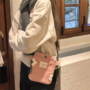 Detailed shot of pink plush crossbody bag with white flower and knot strap
