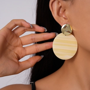 Detail of model wearing gold metal disc and beige striped round acrylic earrings