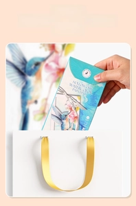 Detailed blue hummingbird watercolor set packaging being placed into a gift bag