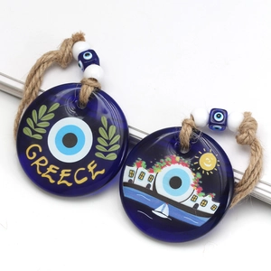 Detail of blue evil eye glass charms featuring Greece text and coastal village illustration