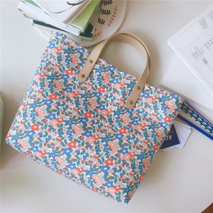 Dettaglio della borsa tote in cotone floreale con manici in pelle kaki e rivetti dorati