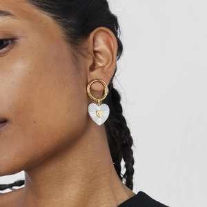 Luxurious gold circular earrings with textured silver heart pendant on a female model