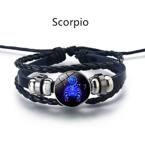 Détail macro du pendentif lumineux Scorpion sur un bracelet en cuir tressé multicouche