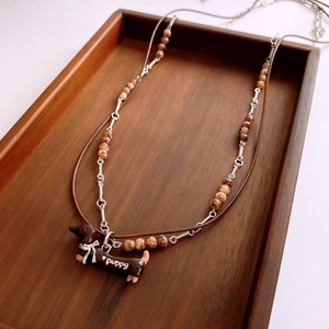 Detailed close-up of dachshund pendant with marble beads on wax rope necklace