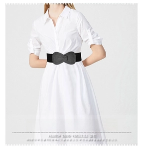 Detail of black elastic waist belt with a flat leather bow tied over a white dress