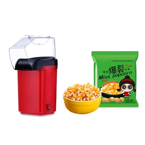 Macro shot of red electric popcorn maker with transparent lid and corn kernels