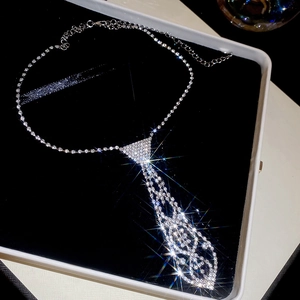 Macro shot of silver crystal necktie necklace with sparkling diamonds on black velvet