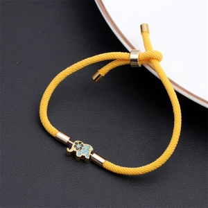 Detailed shot of yellow braided rope bracelet with a gold elephant charm on black leather