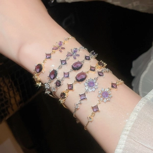 Detail showing stacked zircon bracelets with butterfly and flower motifs on wrist