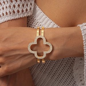 Dettaglio del bracciale rigido dorato a doppio strato con motivo a quadrifoglio