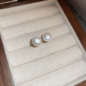 Close-up of elegant round white pearl earrings resting in a premium wooden jewelry box