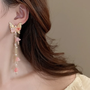 Détail de boucles d'oreilles papillon à pompons avec fleurs roses sur un mannequin
