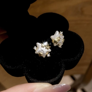 Détail de boucles d'oreilles étoile en or 14 carats avec zircon et perles en boîte
