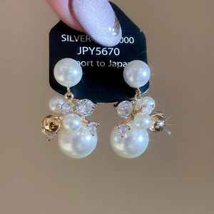 Détail macro des boucles d'oreilles en perles et zircons plaquées or 14 carats