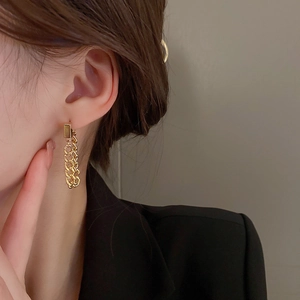 Detail of long golden chain drop earrings on model showcasing a minimalist metallic style