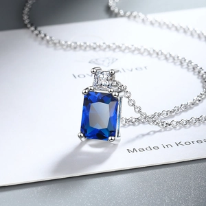 Macro shot of rectangular blue gemstone pendant with silver chain and cubic zirconia detail