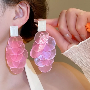Detail of layered pink shell-like disc fringe earrings worn by a model in a boho style