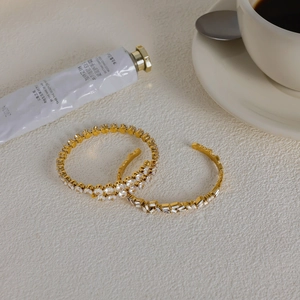 Gros plan de bracelets dorés en zircon avec pierres rondes et rectangulaires sur bureau beige