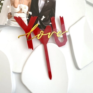Dettaglio macro della decorazione per torta in acrilico rosso YOU e love oro a due strati