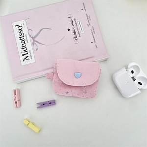 Close-up of pink canvas earphone case with heart button and star charms for AirPods