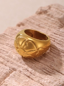 Detailed view of wide gold-plated dome ring featuring embossed heart motifs on stone