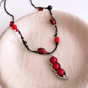 Macro shot of ethnic pea pod pendant with red beads and rhinestones on a ceramic dish