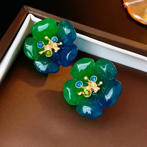 Gros plan de boucles d'oreilles vintage avec fleurs en résine bleu-vert dans un écrin