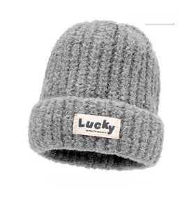 Detail of dark gray chunky knit beanie with textured loop yarn and white Lucky fabric label