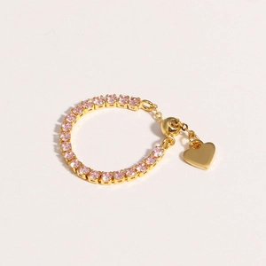 Detail of adjustable gold ring with pink zircon stones and a heart-shaped charm