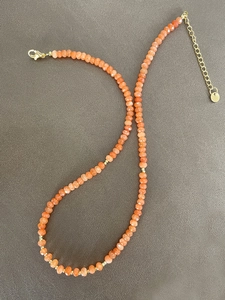 Detail von facettierten orangefarbenen Natursteinperlen an einer vergoldeten Edelstahlkette