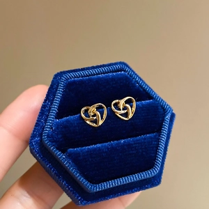 Detailed macro view of golden heart studs in a luxury navy blue velvet gift box