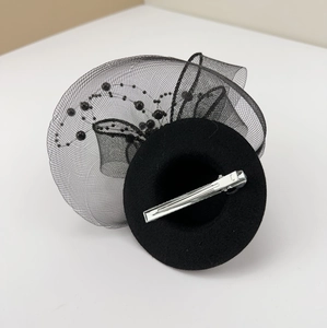Detail of black mini top hat fascinator featuring mesh veil, beads, and metal hair clip