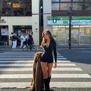 Women's black V-neck button bodycon romper paired with a brown faux fur long coat