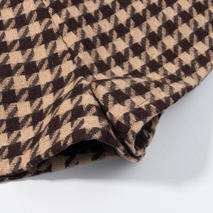 Macro shot of thick brown houndstooth tweed fabric texture and stitching details