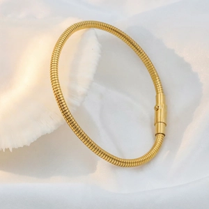 Detail of 18k gold plated titanium steel snake chain bracelet on white silk with shell