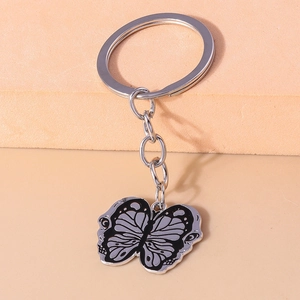 Detailed macro view of a silver butterfly keychain with black enamel wings and metal chain