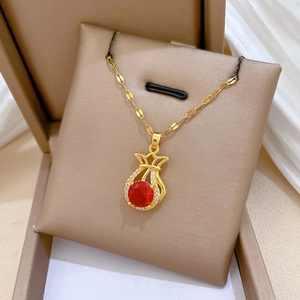 Makroaufnahme von Gold-Glücksbeutel-Anhänger mit rotem Edelstein und Diamanten in Box