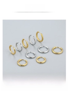 Detail view of twisted and hammered stainless steel hoop earrings in gold and silver finish