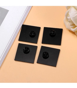 Detail of four black butterfly clutch pin backs on a peach background with floral decor