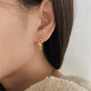 Close-up of a model wearing golden knot earrings made of 925 sterling silver