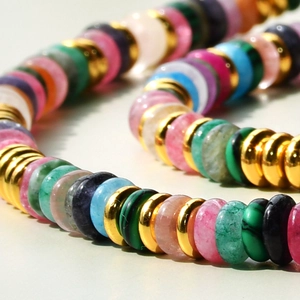 Macro detail of colorful natural stone beads with gold spacers in a wave pattern
